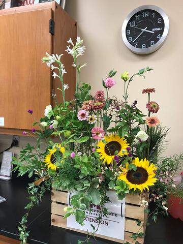 An arrangement of flowers of varying heights on a decorative crate.