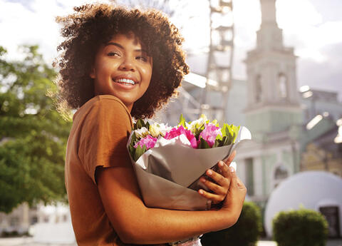 A person holding a bouquet of wrapped flowers.