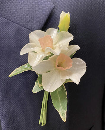 Two white and peach-colored flowers pinned to a blue suit jacket.