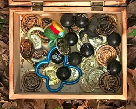 Opened wooden box filled with coins, buttons, and other tradable items.