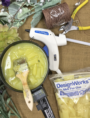 Melting wax pieces in a pot with other materials spread out on a table.