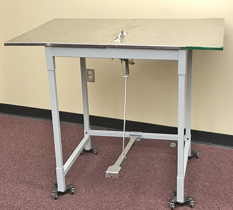 A work table with wheels and a foot pedal.