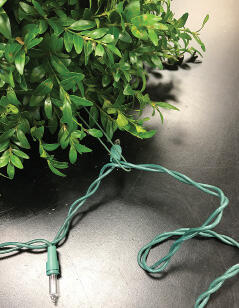 Close-up of a strand of lights attached to the brick with wire.