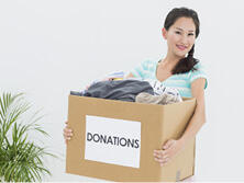A woman carries a donation box filled with fabrics.
