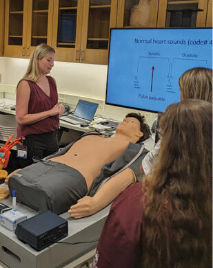 Students and an instructor gather around a CPR mannequin.
