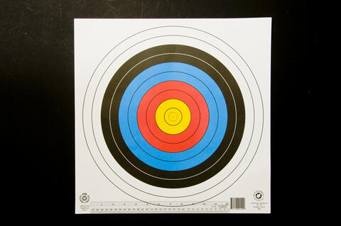 Target with two largest white outer circles, two smaller black circles inside that, two smaller blue circles inside that, two smaller red circles inside that, and three final smaller yellow circles inside that with a ruler at the bottom of the target.