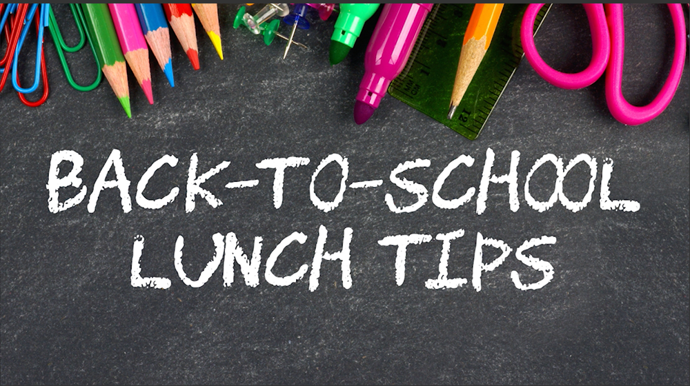 Colored pencils, paper clips, tacks, markers, a ruler, scissors, and a pencil rest at the top of a chalkboard with Back-to-School Lunch Tips written on it in white chalk.