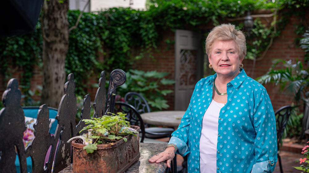 A person standing in a garden beside a plant. 