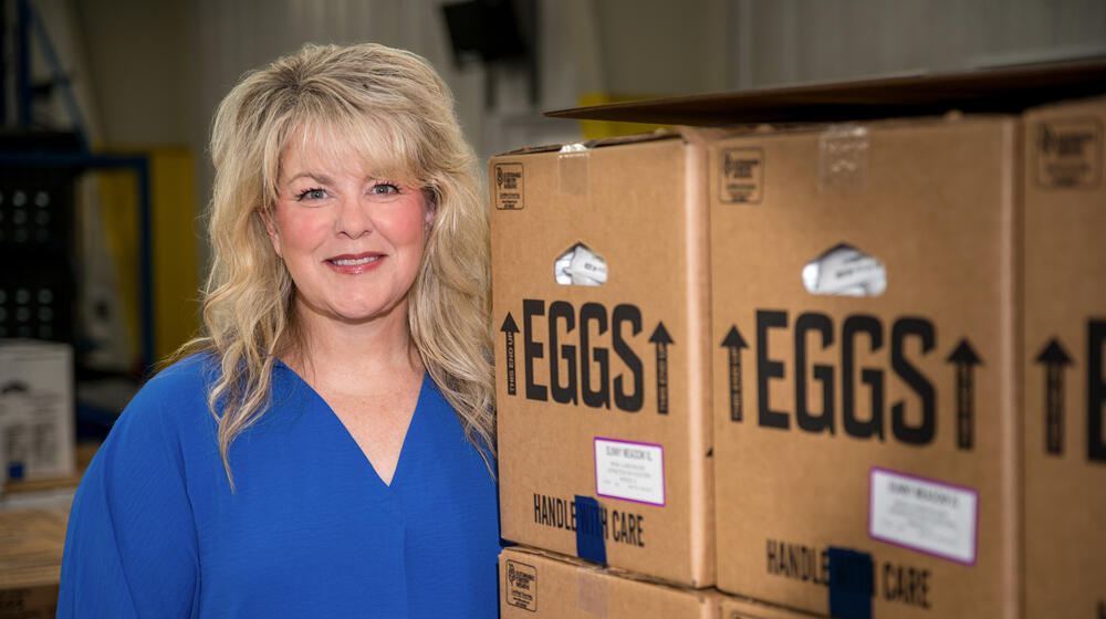 A person standing beside boxes of eggs. 