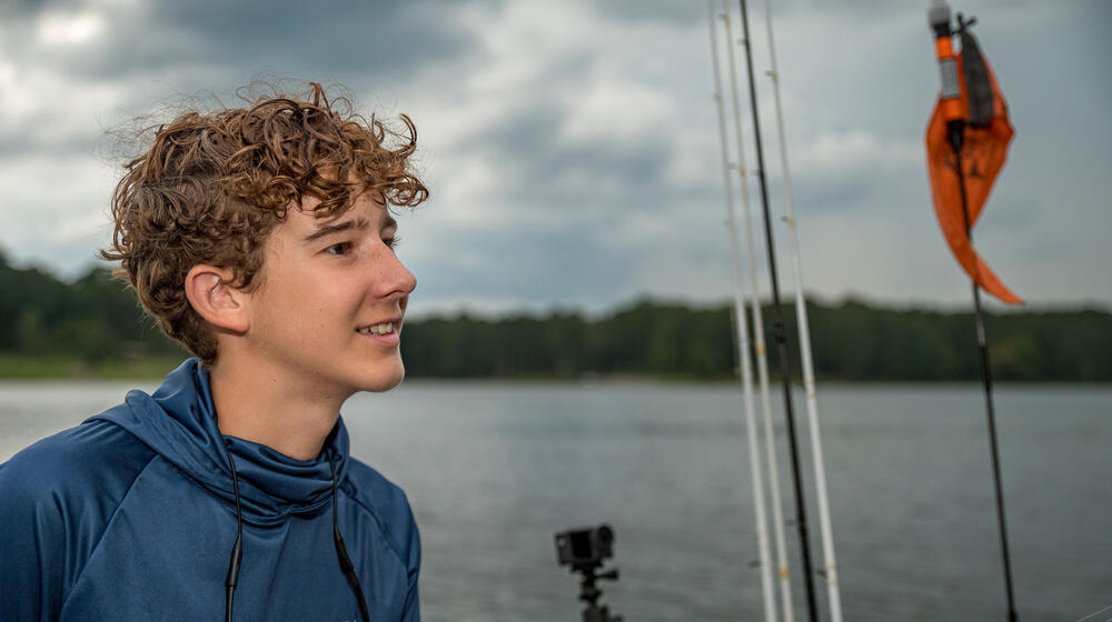 A young person smiles out over the water.