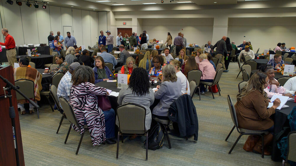 Groups of people seated and standing in a conference room.