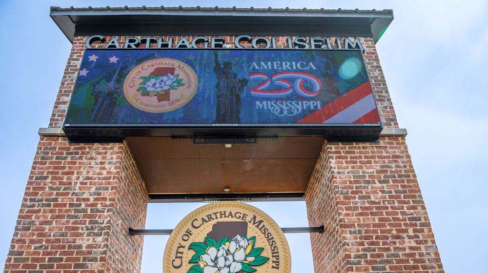 A sign on bricks that lists “Carthage Coliseum,” and “America 250 Mississippi” and shows the City of Carthage seal with a magnolia bloom in the center.