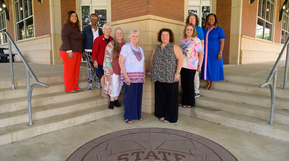 A group of people standing in a V shape on outdoor steps.
