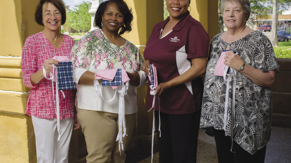 4 women holding mastectomy drain pouch bags—small, square sacks laced with ribbon