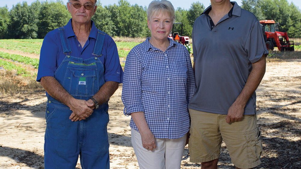 A woman stands between her husband and adult son.