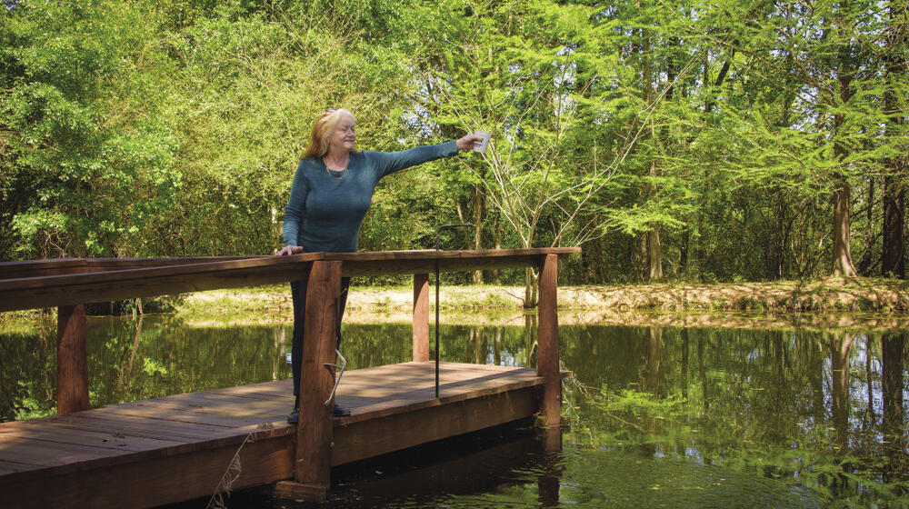 Woman standing on pier in lake holding cup of water