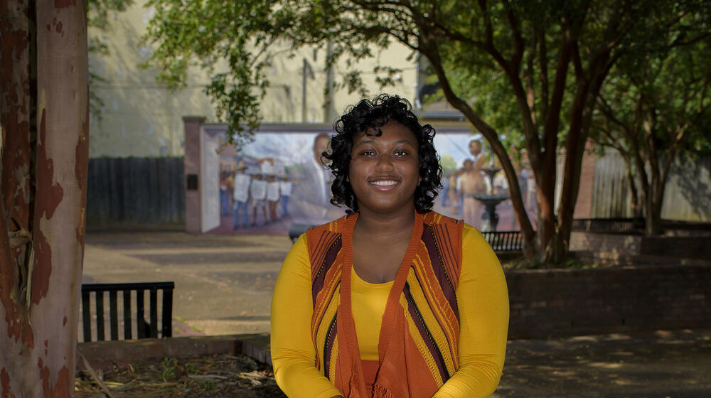 Shandrea Jenkins sitting on a brick planter.