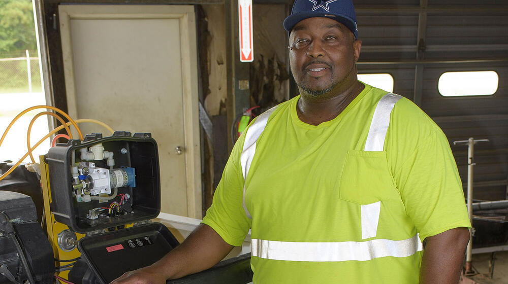 Steven Bell stands beside a truck housing a mosquito sprayer.