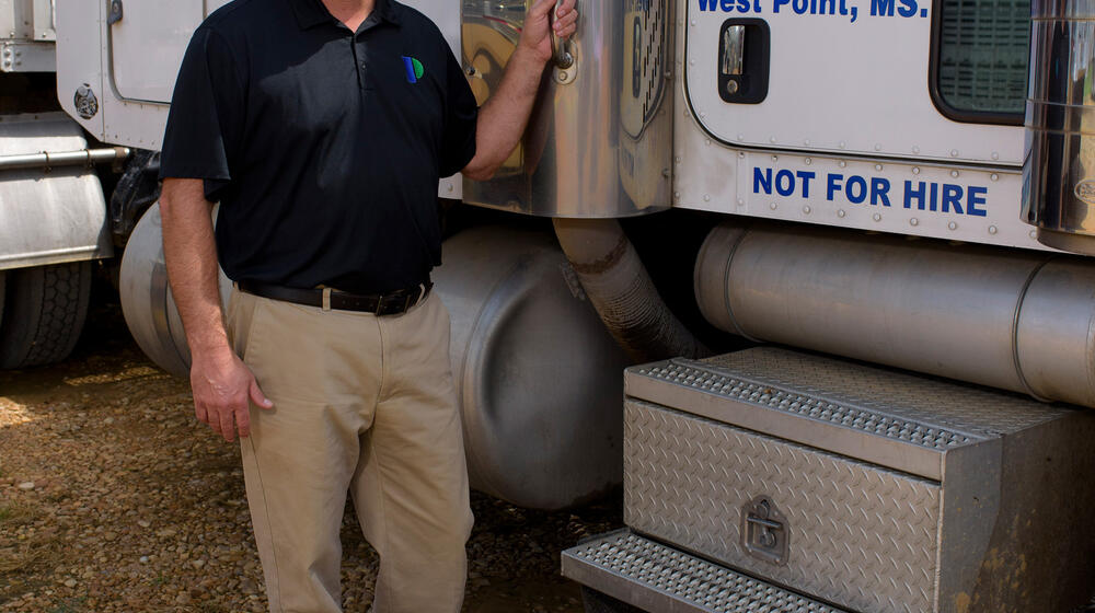 A man stands next to an 18-wheeler truck.