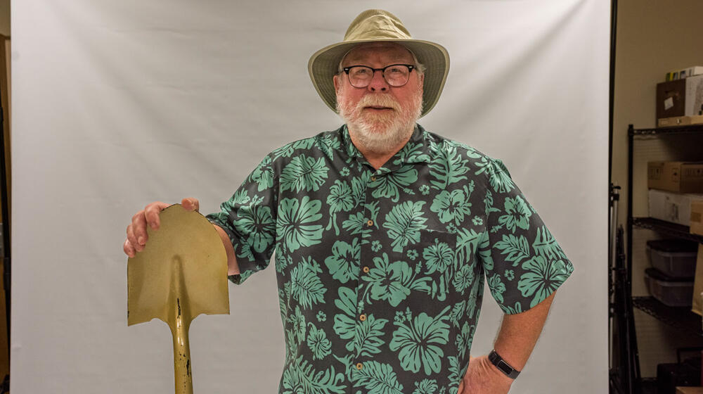A smiling man wearing a cowboy hat and Hawaiian shirt.