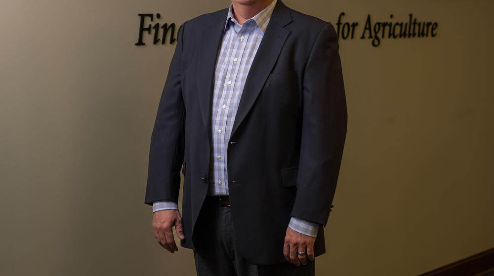 A man standing inside in front of the Southern AgCredit wordmark on a wall.