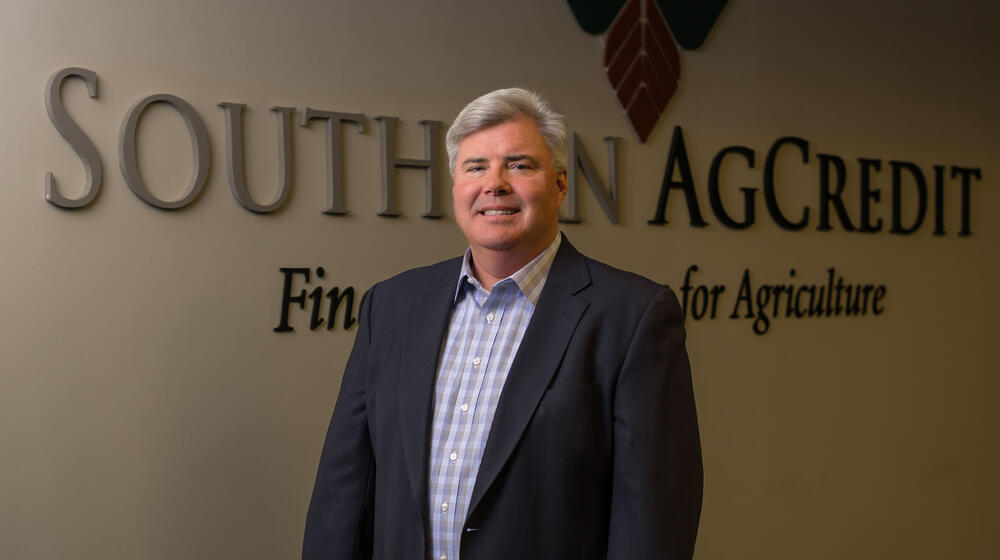 A man standing inside in front of the Southern AgCredit wordmark on a wall.