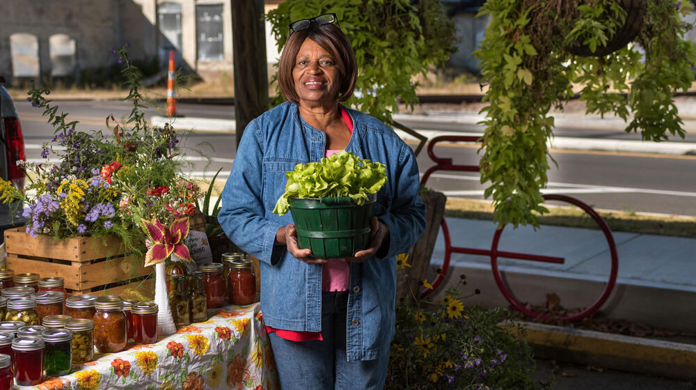 A woman smiling and holding a planter full of lettuce.