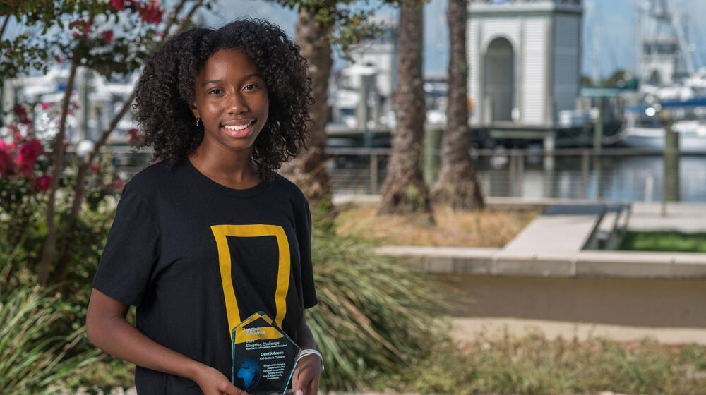 A young woman smiling and holding a trophy.