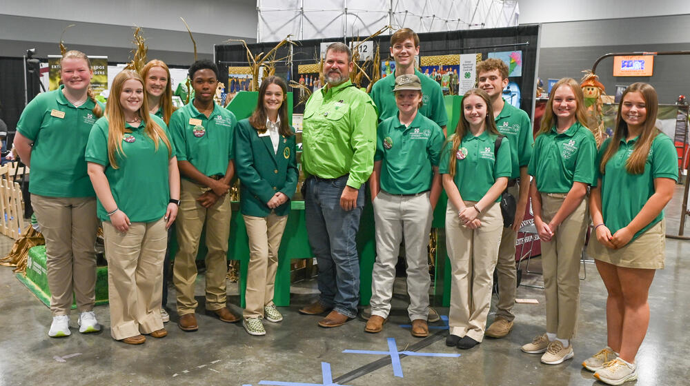 A large group of people, standing, smiling, and wearing green shirts.