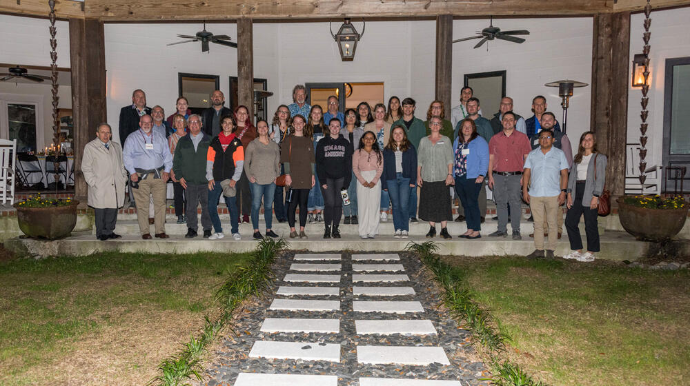 A large group of people standing on a covered patio.
