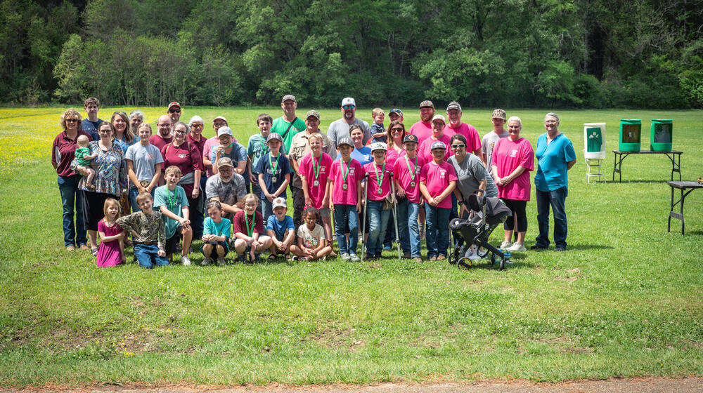 A large group of adults and children gathered on a grassy plain.