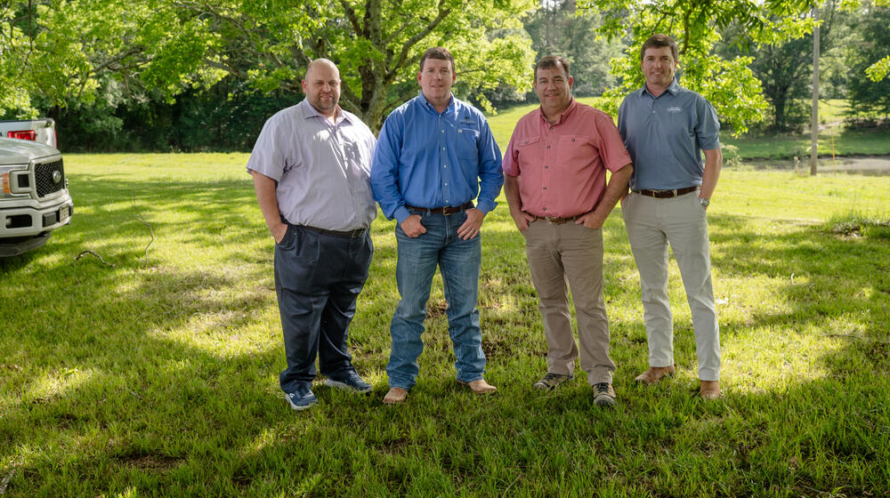 Four people standing outside, hands in their pockets.