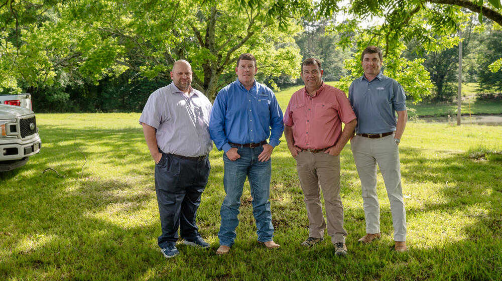 Four people standing outside, hands in their pockets.