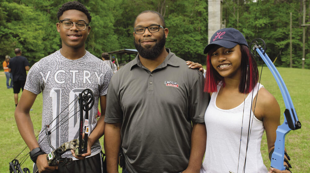 A 4-H volunteer leader with two 4-H members at a 4-H Shooting Sports event.