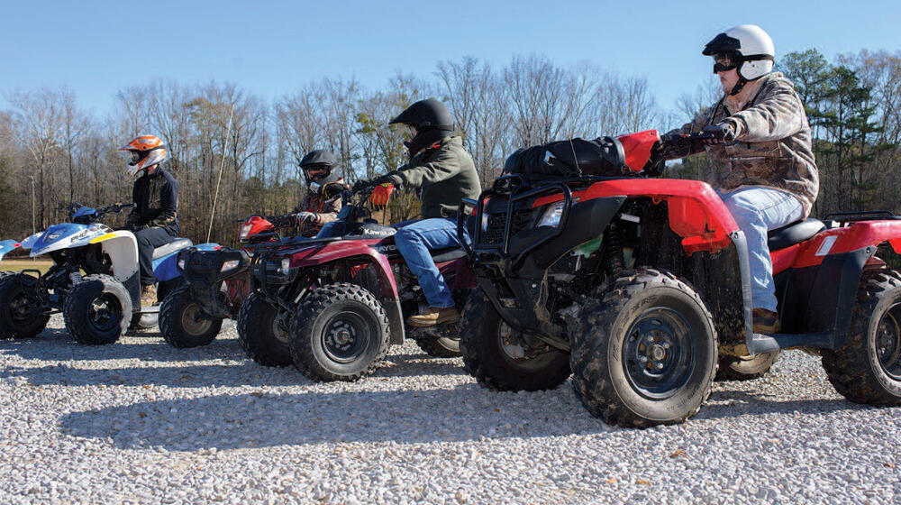 Several men on ATVs lined up.