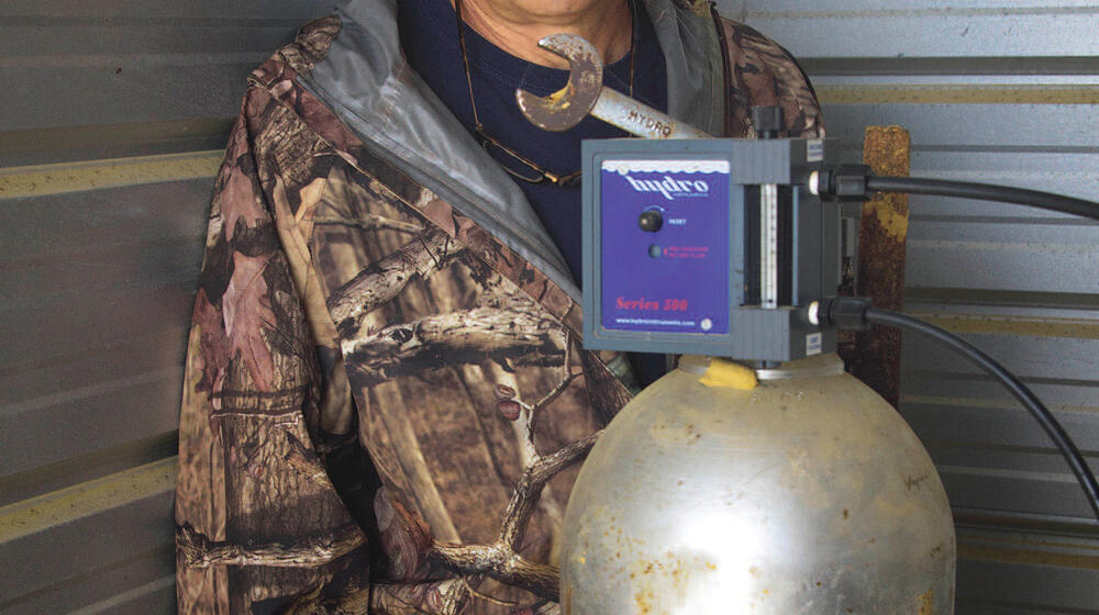 A man stands behind a piece of machinery.