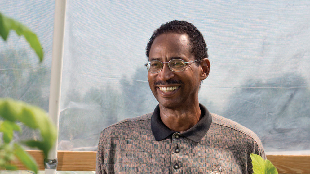 A man holding a styrofoam cup with a plant sprout.