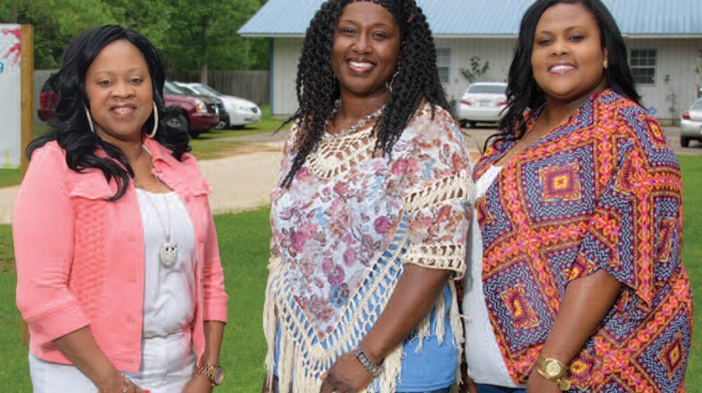 Three smiling women stand next to each other.