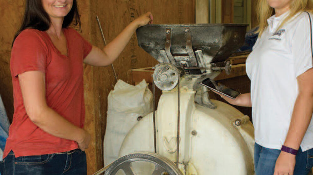 Two women stand on either side of a machine.