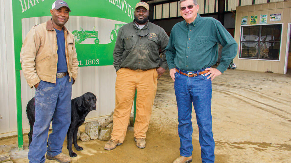 Three men and a black dog stand in front of a sign that reads "Dantzler Phillips Pilkinton."