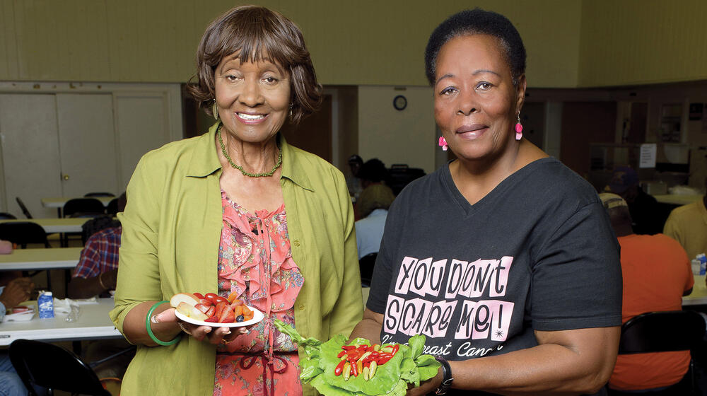 Two elderly women display their healthy food choices.