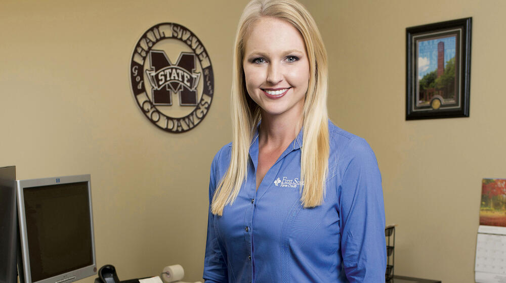 A smiling woman in a blue shirt poses for the camera.