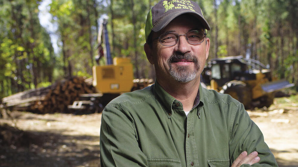 A man stands near a logging operation.
