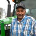 A smiling man standing in front of a green tractor.