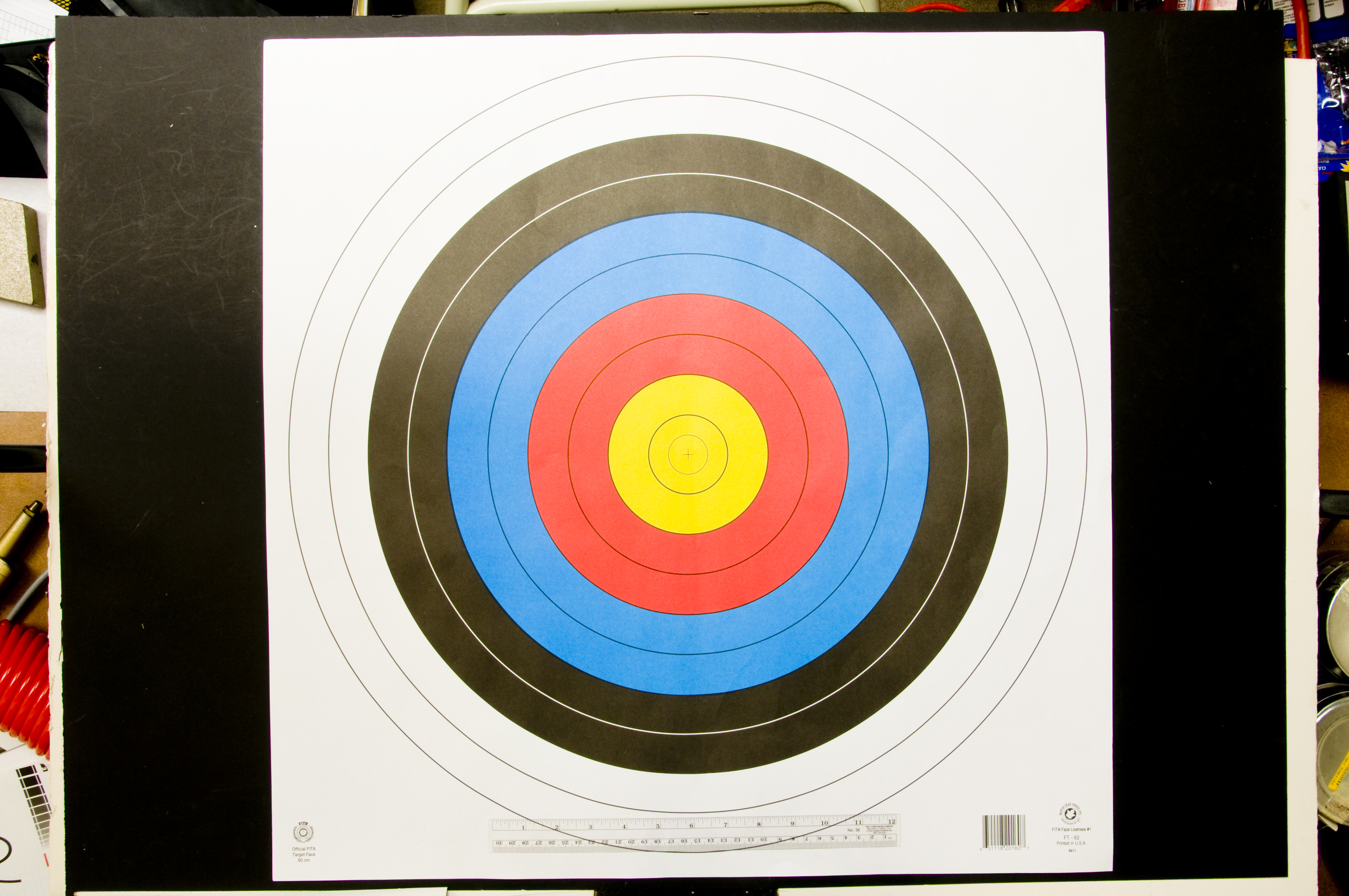 Target with two largest white outer circles, two smaller black circles inside that, two smaller blue circles inside that, two smaller red circles inside that, and two final smaller yellow circles inside that with a ruler at the bottom of the target.